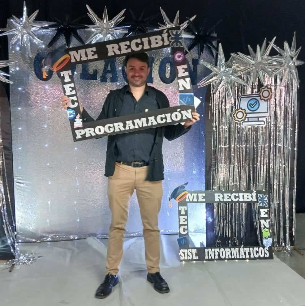 Hombre en evento de tecnología con decoraciones festivas y señalización de programación.